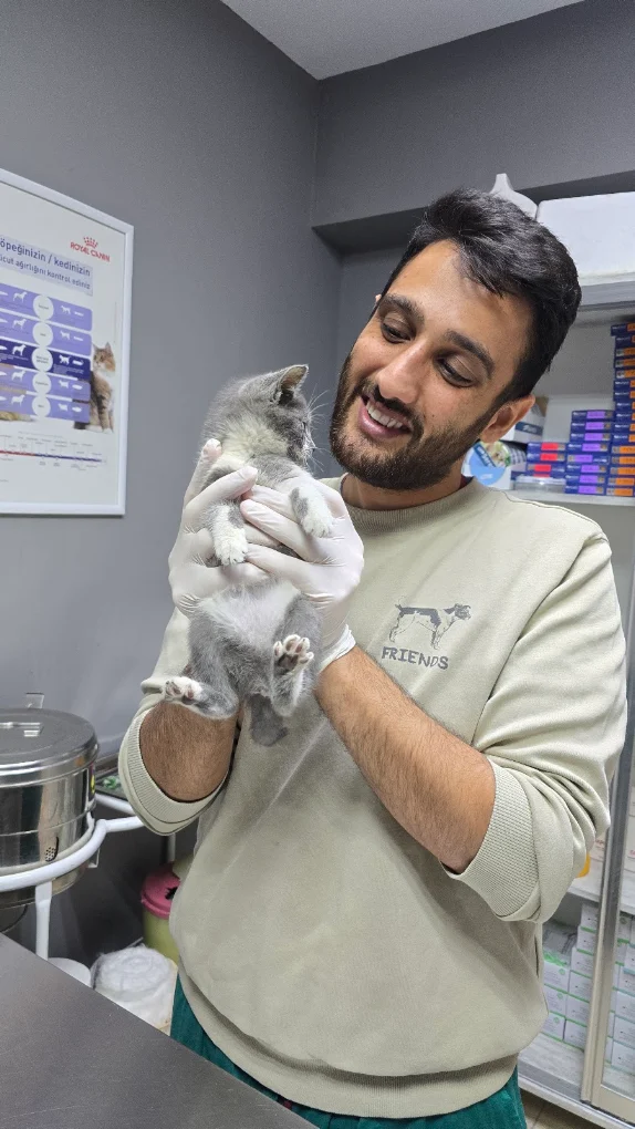 Vetpet Veteriner Kliniği hekimi, muayene sonrası gülümseyerek yavru kediyi kucağında tutuyor