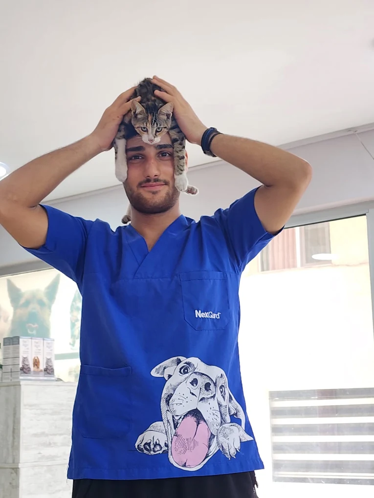 Vetpet ekibinden bir üye, omuzlarında duran kediyle gülümsüyor